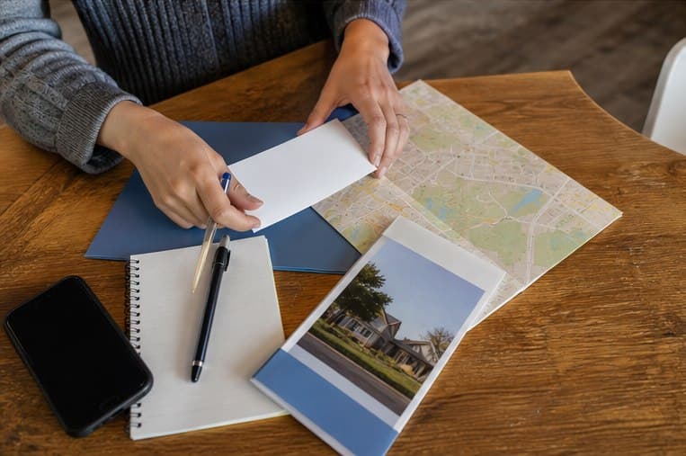 Hands assembling a clinic introduction packet beside a local map and notebook